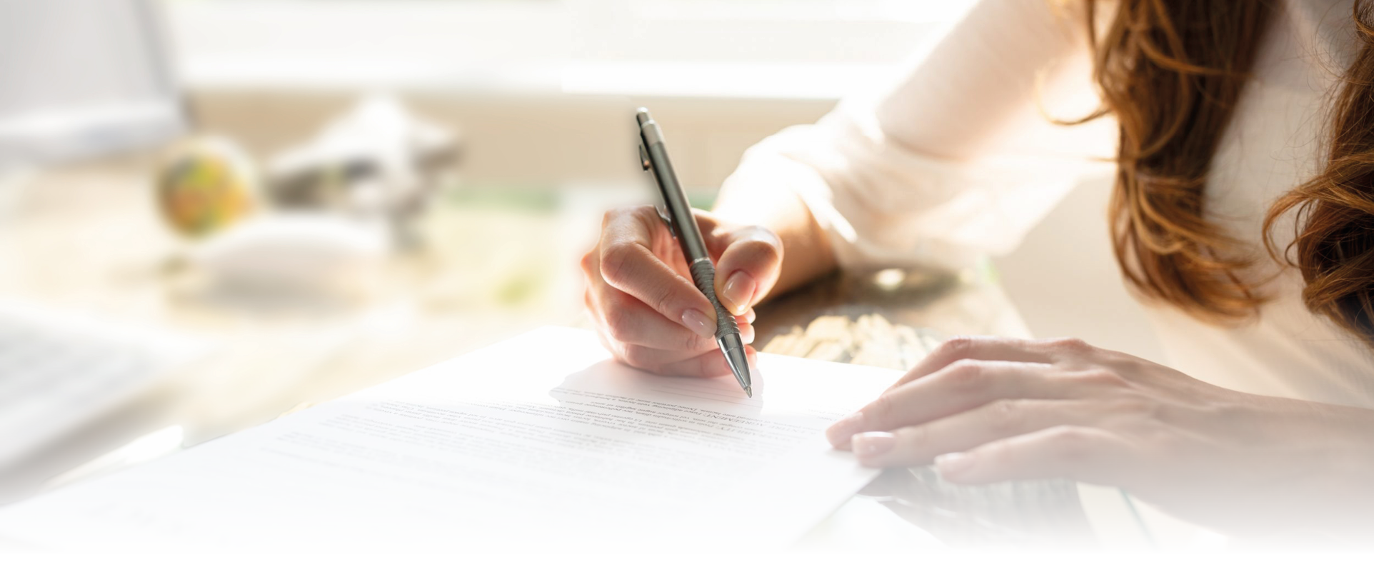 Close-up Of Businesswoman's Hand Signing Contract With Pen Over Desk In Office